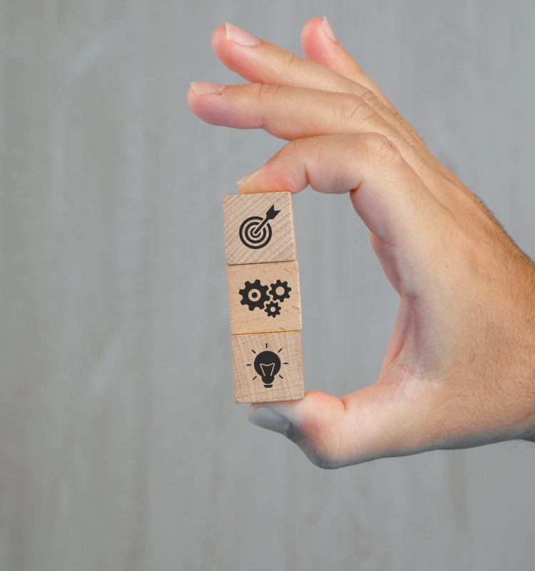 Business concept on grey background side view. hand holding wooden cubes with icons.